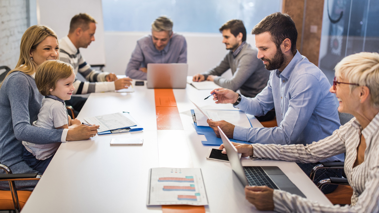 woman with child on lap, working with team at conference table